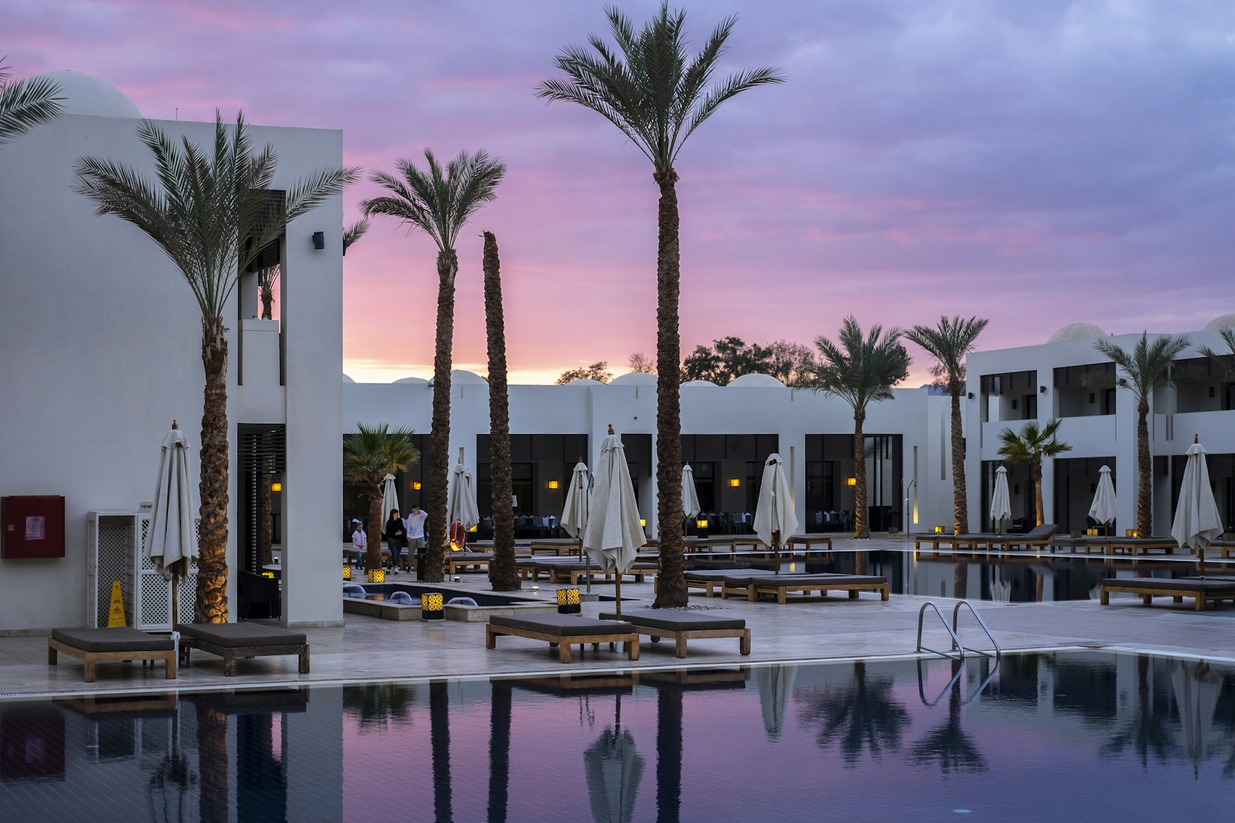 Palm-lined hotel pool and architecture at dusk